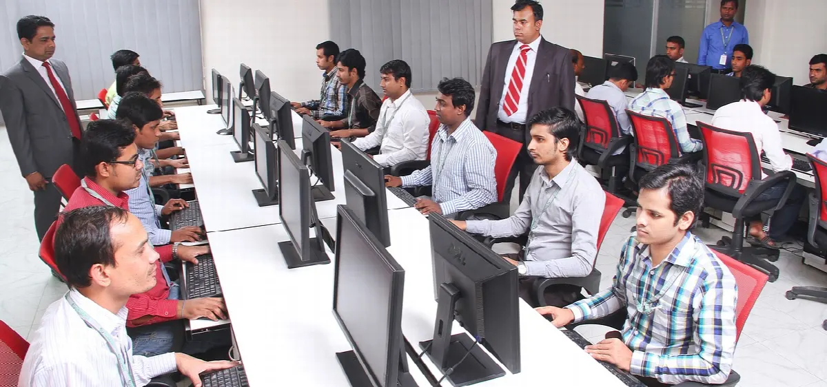 Sala de aula com computadores e participantes atentos